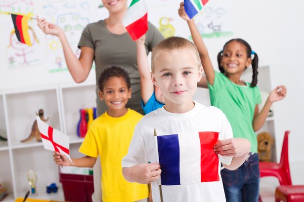 Children in a classroom holding national flags while learning languages